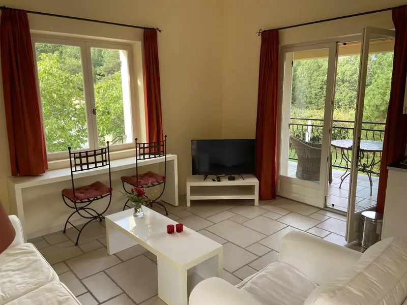 De woonkamer met witte banken, twee smeedijzeren stoelen en de open deur naar de loggia